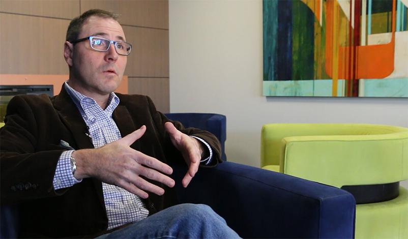 Mark Latta, sitting in a chair at the Mount Mercy graduate center and talking